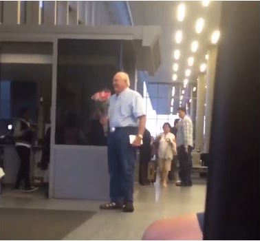man waiting at airport with flowers video