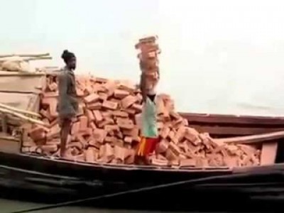 A woman stacks  unprocessed bricks