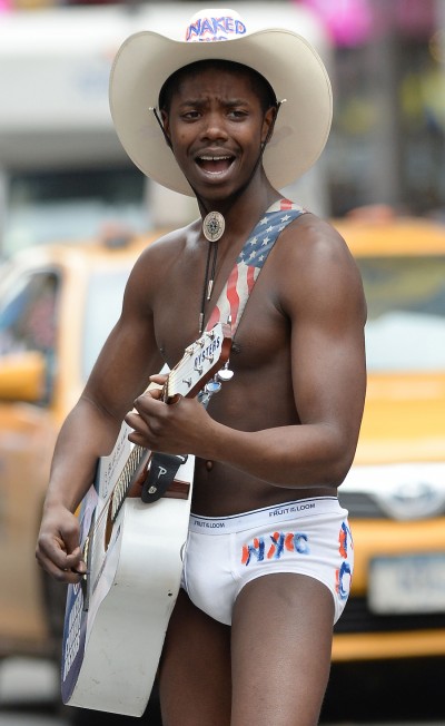 Titus Gandy known as the "Black Naked Cowboy" performed for tourists in Times Square.